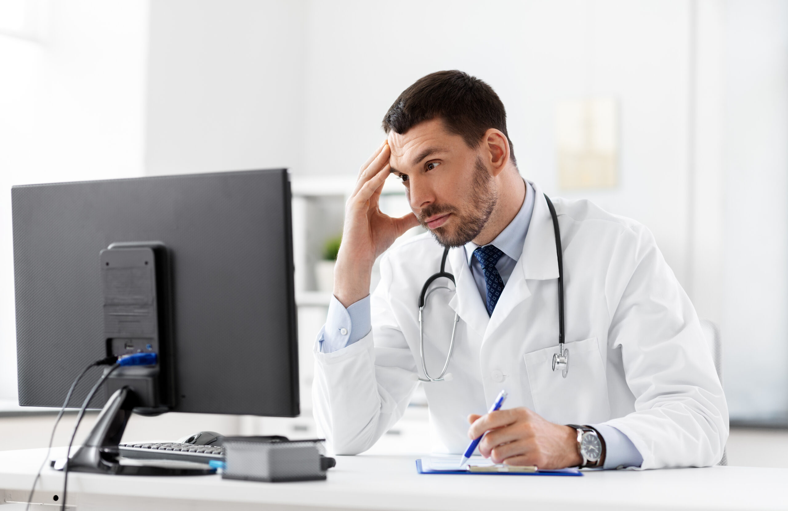 doctor with clipboard and computer at hospital